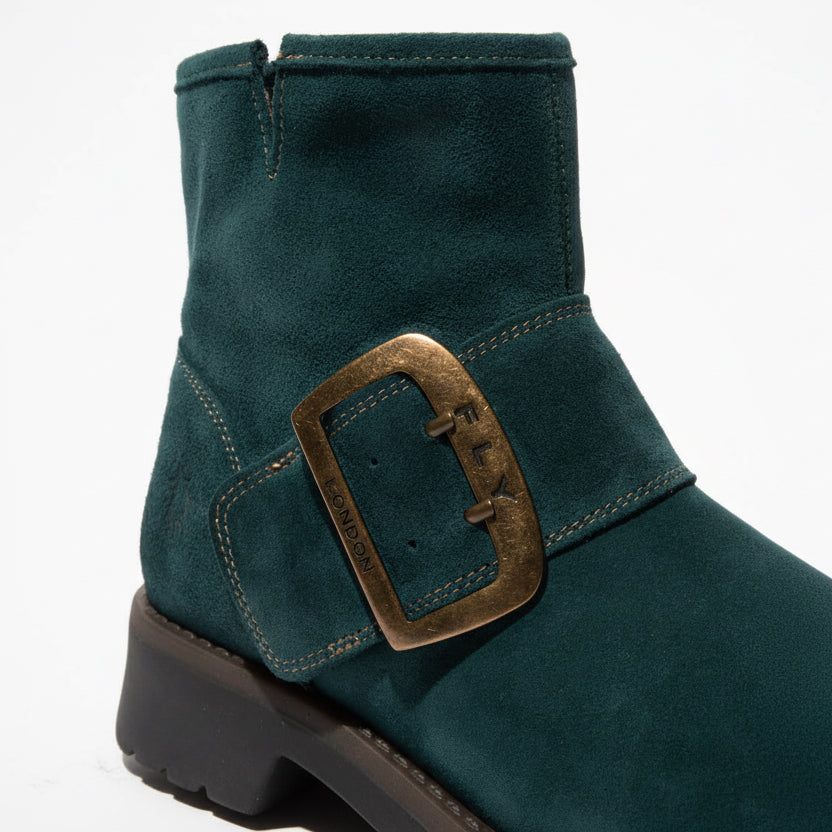 Green ankle boot with a gold buckle on a white background
